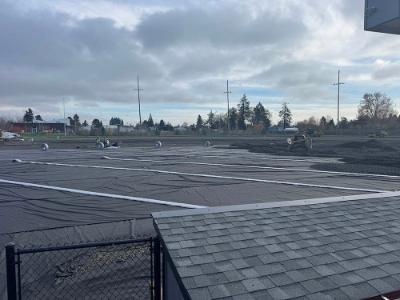 Black plastic tarp is laid on the excavated ground of the Chemeketa Baseball field in preparation to be covered with artificial turf.